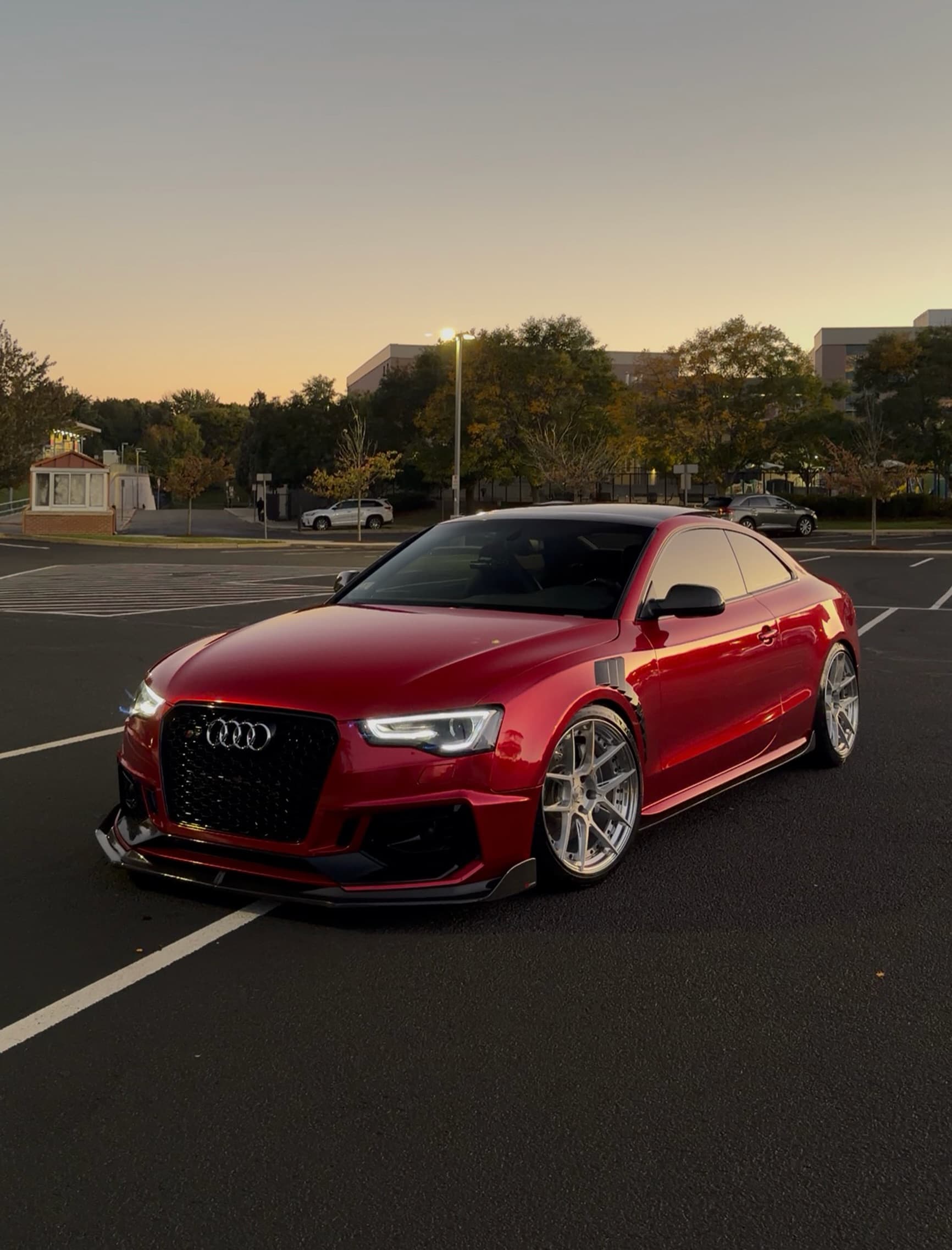 Red Audi coupe with a black roof, parked in the evening light.